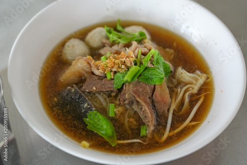 The closed up of Thai noodles. Asian noodle soup with beef meatball with fresh vegetable on wood table. 
