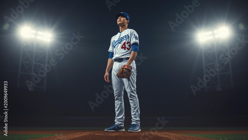 Baseball player stands on field at night