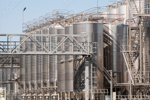 Fotografija Steel tanks stand in a large industrial site with clear blue sky above and metal