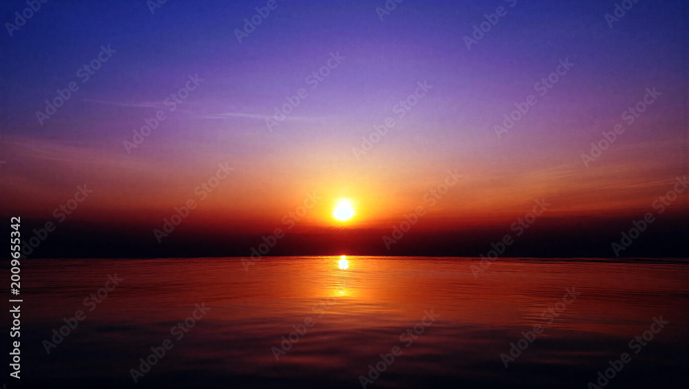 Obraz premium Stunning sunset over calm water with vibrant orange and purple sky colors creating a peaceful ambiance