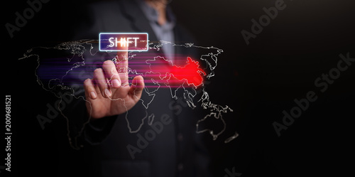 Fotografija Finger pressing SHIFT above the digital world map showing power shifting from West to East
