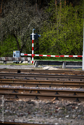 Closed railway crossing barriers and warning signals with tracks in the foreground