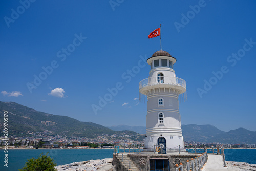 Bild auf Leinwand White lighthouse with Turkish flag in Alanya harbor on sunny day