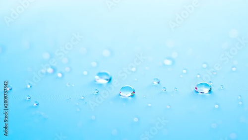 High-quality macro shot of clear water droplets and bubbles on a soft light blue background. Perfect for beauty, skincare, medical, and purity-themed concepts