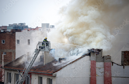 A fireman is fighting to extinguish fire on the roof of a building