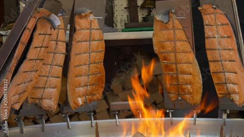 Traditional salmon fillets roasting over open fire at outdoor grill