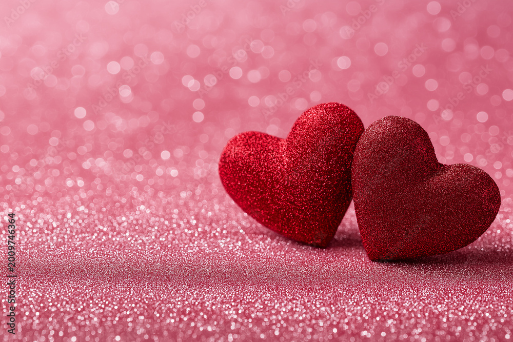 Fototapeta premium two red hearts on a pink glittery background with space for text, creating a bokeh and blurred effect, perfect for valentine's day