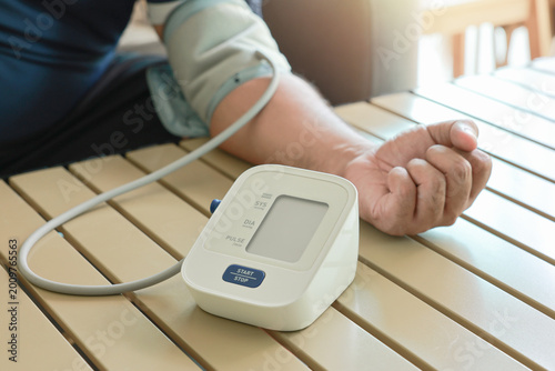 Fotografie Unrecognizable man measuring blood pressure with digital sphygmomanometer at home