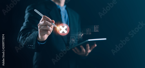 Businessman using stylus on tablet to mark rejection with glowing cross icon on digital checklist, representing validation failure, workflow issues, and compliance error in a corporate environment.