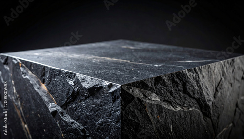 Striking geometric dark stone podium with sharp angular edges and flat smooth display surface, deep charcoal black and dark slate grey tones