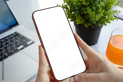 Hand holding orange phone blank white screen mockup office desk