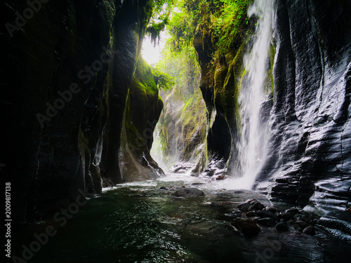A majestic waterfall tumbles into a serene river, carving through a breathtaking hidden canyon, showcasing the raw, ancient power and ethereal beauty of the natural world