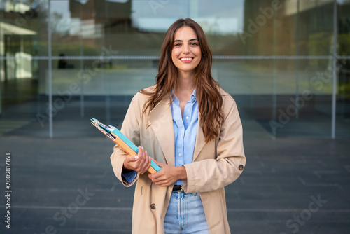 Confident businesswoman smiling holding file folders outdoors