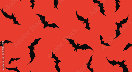 Halloween background featuring a seamless pattern of black flying bat silhouettes over a bright solid red color for spooky party decor.