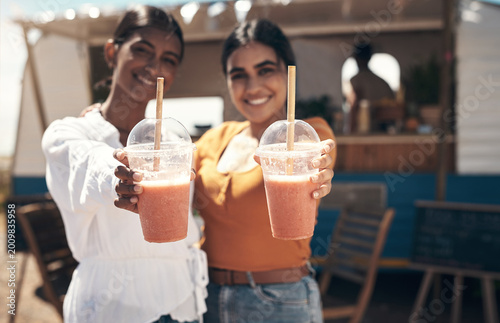 Fotografie Portrait, women and happy with smoothie outdoor by food truck for wellness, bonding or weekend break