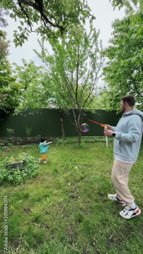 Toddler Chasing Soap Bubble in Green Backyard Garden