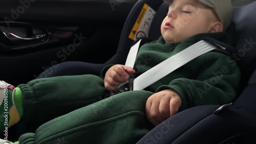 Sleeping baby in car seat with safety harness