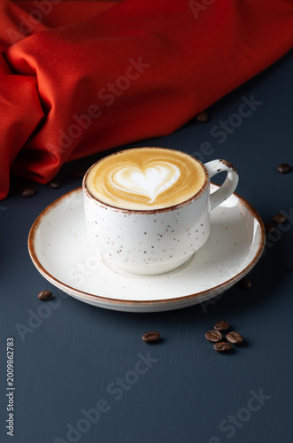 Heart Latte Art in a White cup with coffee beans on wooden table