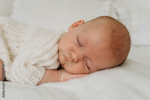 a newborn baby is sleeping, a sweet healthy baby's sleep on a white bed, space and room for text