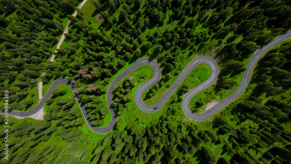 Fototapeta premium Winding mountain road, aerial view of a serpentine asphalt highway through a dense green forest, scenic travel route for adventure and exploration, nature landscape photography