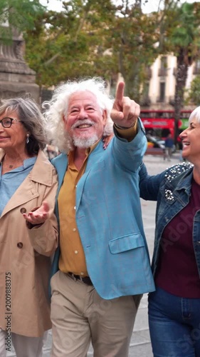 Group of stylish senior friends enjoying their vacation. Happy retired man pointing at something with his friends during a city tour
