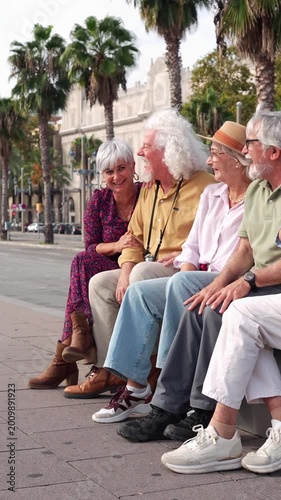 Group of elderly friends sitting on a bench in a sunny city street, laughing and talking. Happy retirement lifestyle and social connection