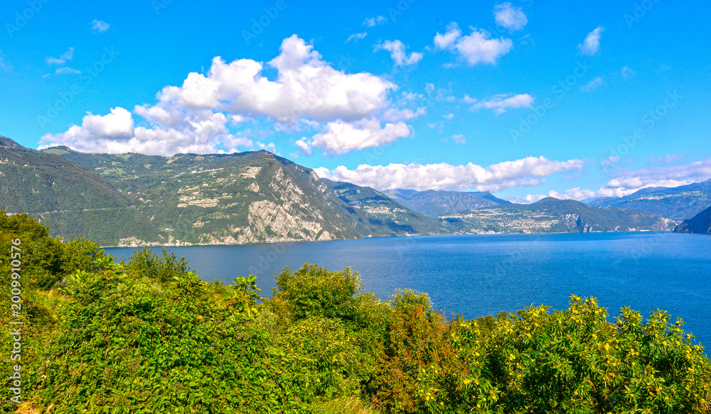 Obraz premium Weites Landschaftspanorama des Iseosees mit blauem Wasser und umliegenden Bergen, Italien