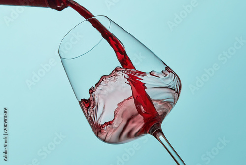 Red wine pouring into tilted glass, dynamic splash motion