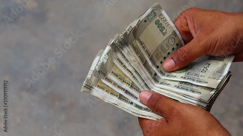 Close up of an Indian man counting five hundred rupee notes outdoors, male hands holding and counting Indian currency cash, finance and investment concept

