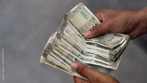 Close up of male hands holding a stack of Indian five hundred rupee notes, hands counting cash currency, business finance and investment concept
