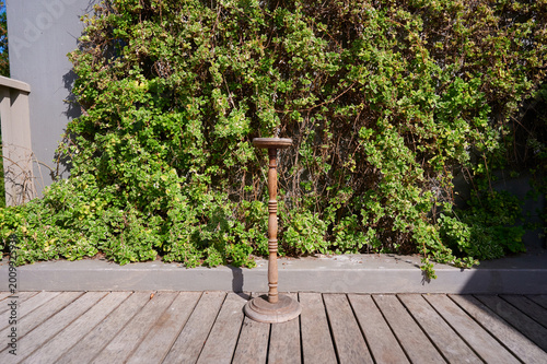 Foto Wooden stand sitting on deck in front of greenery