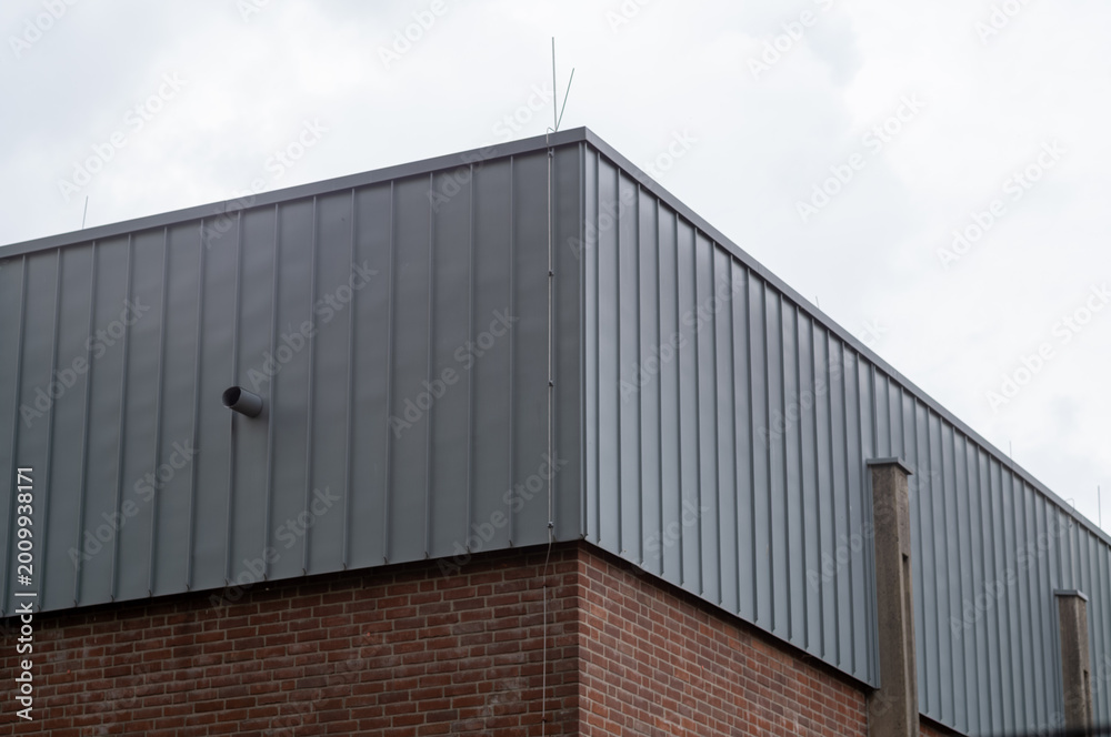 Obraz premium Modern industrial building wall showing corrugated metal and brickwork