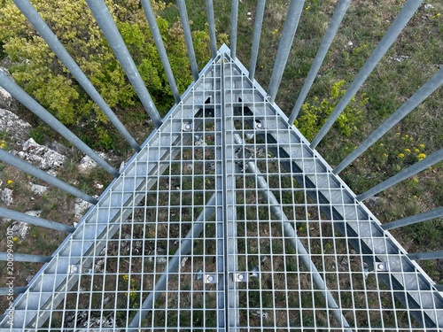 Mesh artificial background. Top view on metal grate floor and railings with bushes and rocks under it.