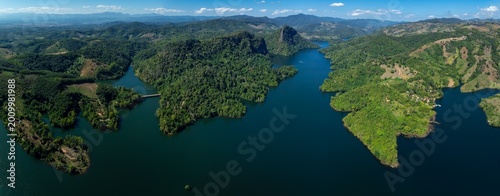 Panoramic View Of A Winding River Flowing Through Lush Tropical Mountains Under A Clear Blue Sky