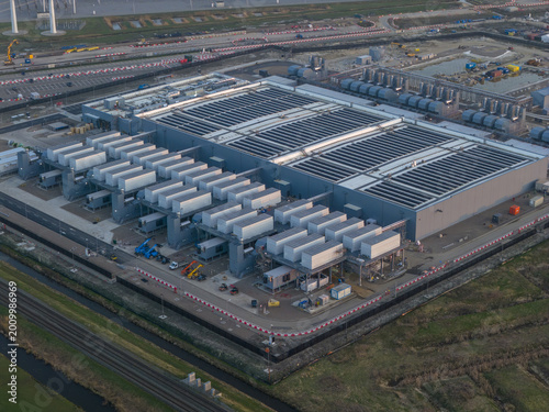 Aerial view of the Google data center with extensive cooling systems, industrial infrastructure and wind turbines in the distance.