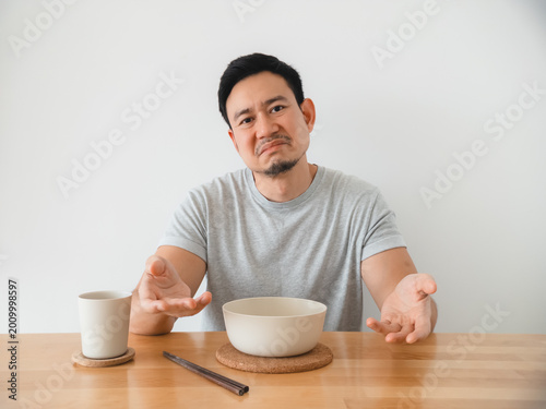 Asian man consumer shrugging after bland bite, questioning gesture