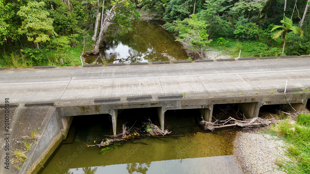 Fototapeta premium Aerial View of a Concrete Bridge Over a Tropical Rainforest Creek