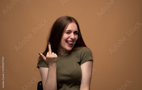 Foto Young woman winking and playfully sticking out her tongue, showing a rude middle