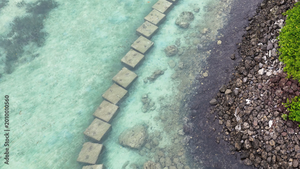 Fototapeta premium Aerial View of Submerged Concrete Block Pathway Along a Rocky Shoreline