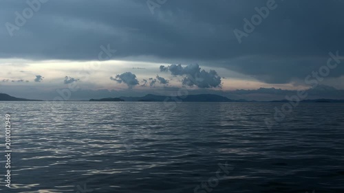 POV from a boat in a Gloomy seascape. Reflective waters under darkening clouds. 