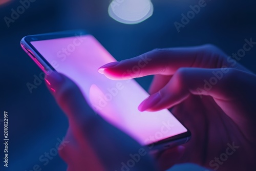 Person using a smartphone in the evening with colorful light effects shining on the screen