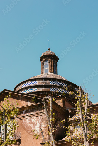 Detailed view of an old stone building dome decorated with blue and white zigzag ceramic tiles under a clear blue sky.