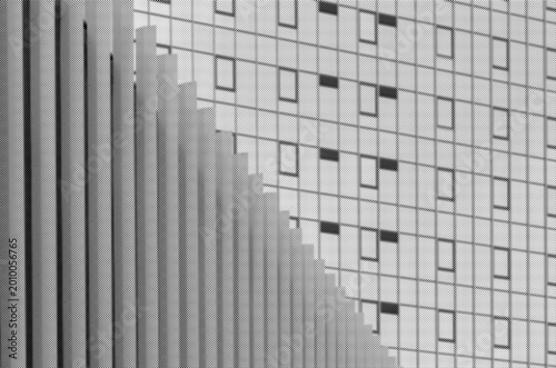 Abstract modern building facade with repeating windows and vertical lines. Geometric urban architecture in black and white with a grid pattern.