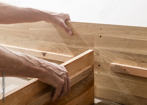 Hands assembling wooden furniture. Close up of carpentry work with boards and joinery. DIY home improvement and woodworking in a studio setting..