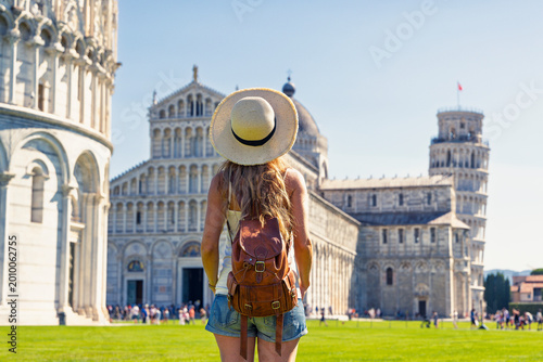 Foto back view of young female traveler with backpack and straw hat looking at the le