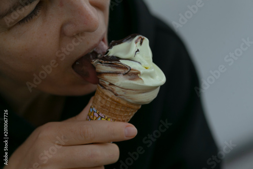 Woman enjoying treat, Urban scene with woman eating dessert, Closeup of woman savoring dipped ice cream cone, Casual woman in city relishing vanilla swirl with chocolate coating in waffle cone