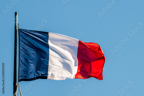 Drapeau français en mouvement sous l'effet du vent sur fond de ciel bleu, France