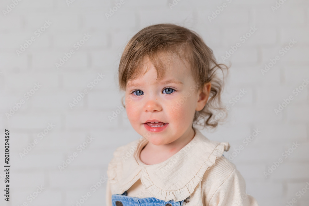 Naklejka premium portrait of a little girl with blond curly hair and blue eyes