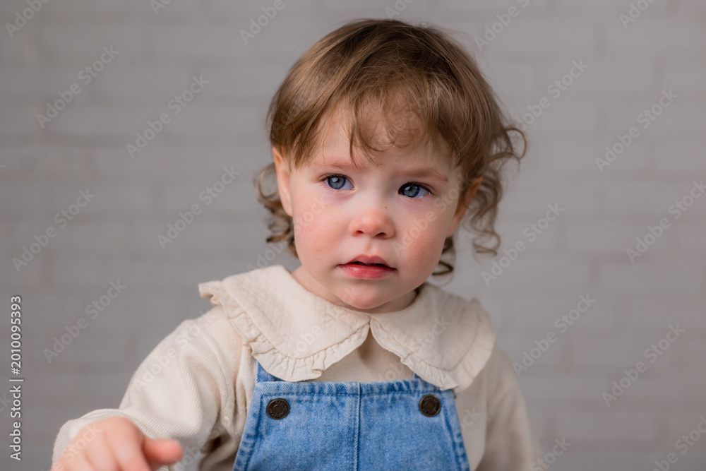 Naklejka premium portrait of a little girl with blond curly hair and blue eyes