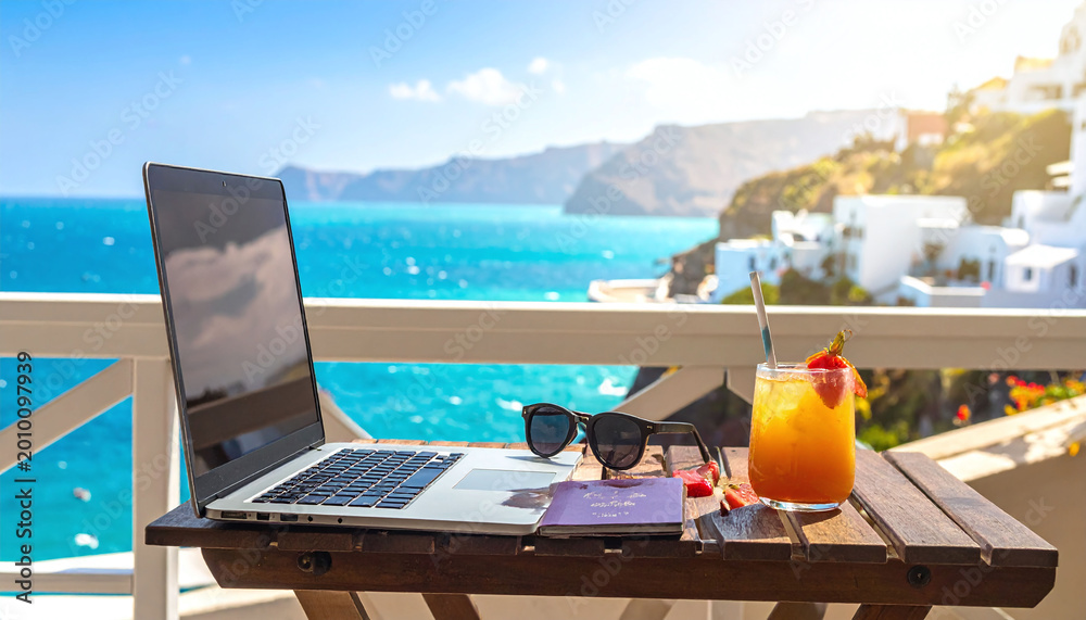 Fototapeta premium Remote work paradise a laptop and cocktail on a balcony overlooking a bright turquoise sea. Ideal for themes of travel, freedom, digital nomadism, and Mediterranean summer vacations.